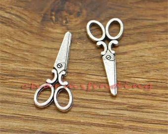 May include: Two silver-toned metal scissor charms with intricate details. These charms are perfect for adding a touch of whimsy to jewellery projects.