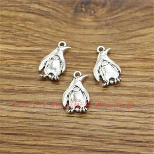 May include: Three silver penguin charms featuring a detailed design. The charms are ideal for adding a whimsical touch to jewellery or crafts.