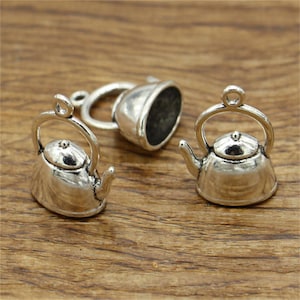 Puede incluir: Tres encantos de tetera plateados. Los encantos están detallados con un pico, un asa y una tapa. Los encantos son perfectos para agregar un toque de fantasía a las joyas o las manualidades.