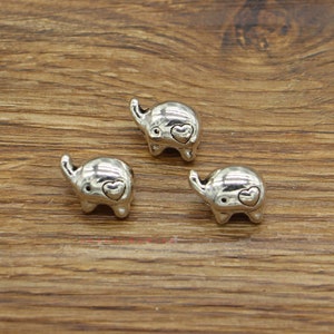 May include: Three silver charm pendants shaped like elephants with a small heart on each elephant's back.
