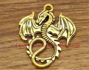 May include: Gold-toned metal dragon charm with wings outstretched and a curled tail. The dragon has a detailed design with scales and a textured surface.