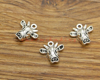 May include: Three silver cow head charms with a detailed design. The charms have a loop at the top for attaching to jewelry or other crafts.