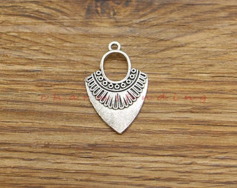 May include: Silver pendant charm with a decorative design featuring a circle and a pointed bottom. The pendant has a vintage look.
