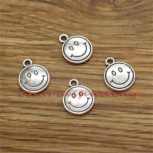 May include: Four silver-toned smiley face charms with a loop for attaching to jewelry or other crafts.