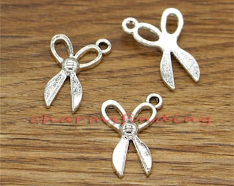 May include: Three silver-toned metal charms shaped like scissors. The charms have a detailed design and are perfect for adding a unique touch to jewellery or crafts.