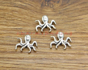 May include: Three silver octopus charms on a wooden surface. The octopus charms are detailed and have eight tentacles.