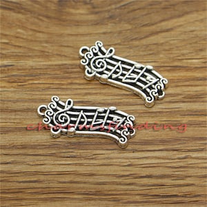 May include: Two silver-toned metal charms shaped like musical notes on a treble clef staff. The charms are detailed with musical notes and a treble clef.