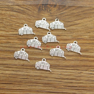 May include: Ten silver-toned metal charms shaped like vintage campers. Each charm has a loop at the top for attaching to a necklace, bracelet, or other jewelry.