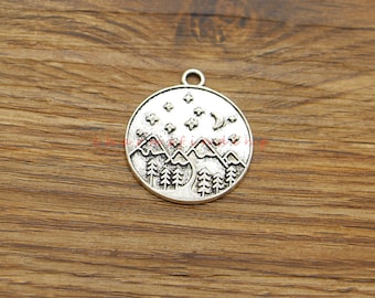 May include: Silver charm featuring a mountain range, crescent moon, and stars design. The charm is round and has a loop at the top for attaching to a necklace or bracelet.