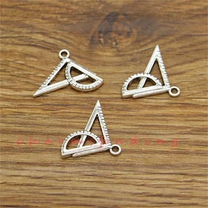 May include: Three silver-toned protractor charms with a hole at the top for hanging. The protractors are in the shape of a triangle with a semi-circle on the inside.