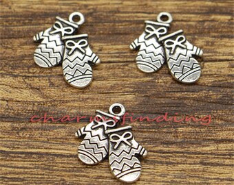 May include: Three silver charm pendants in the shape of mittens. Each mitten has a white and gray striped pattern and a small bow on the top.