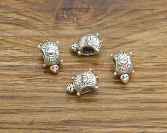 May include: Four silver turtle charm beads with a hole in the center for stringing on a bracelet or necklace.