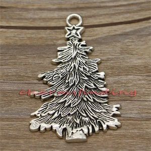 Pode incluir: Um pingente prateado de árvore de Natal com uma estrela no topo. O pingente tem uma argola para pendurar e galhos texturizados detalhados. Ideal para joias ou projetos de artesanato com tema de feriado.