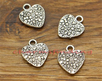 May include: Four silver heart-shaped charms with a textured surface. Each charm has a small loop at the top for attaching to jewelry or other crafts.