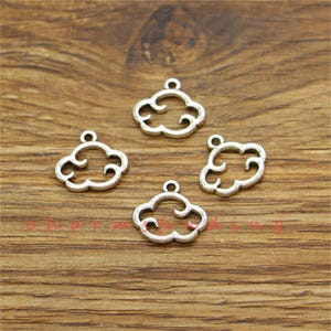 May include: Four silver-colored cloud charms with a loop at the top for hanging. The charms are arranged on a wooden surface. These charms are suitable for jewelry making or other craft projects.