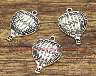 May include: Three silver-toned hot air balloon charms with a detailed design. The charms are perfect for adding a whimsical touch to jewelry or crafts.