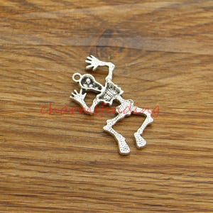 May include: Silver-toned skeleton charm featuring a detailed design. The skeleton is depicted in a jumping pose with arms raised.