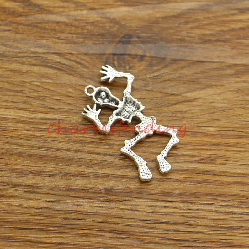 May include: Silver-toned skeleton charm featuring a detailed design. The skeleton is depicted in a jumping pose with arms raised.
