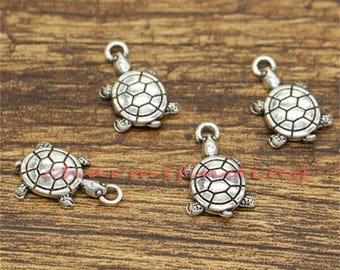 May include: Four silver turtle charms with a detailed shell design. The charms have a loop at the top for attaching to jewelry or other crafts.