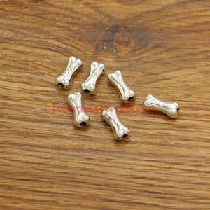 以下が含まれることがあります： 銀製の骨の形をしたビーズ。ジュエリー作りやクラフトプロジェクトに最適です。