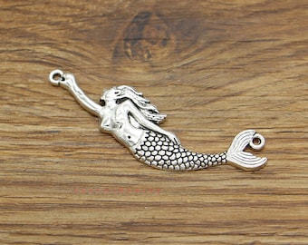 May include: Silver-toned mermaid charm with a detailed design, featuring a flowing tail and a raised, textured surface. The charm has a loop at the top for attaching to jewelry or other crafts.