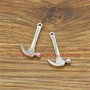 May include: Two silver-toned hammer charms with a loop at the top for attaching to jewelry or other crafts.