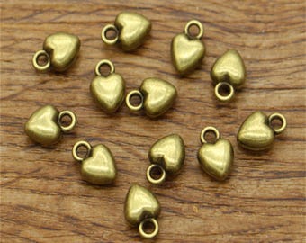 May include: A collection of 12 antique gold heart-shaped charms with a loop for attaching to jewelry or crafts.