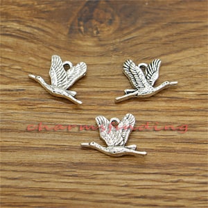 May include: Three silver-toned metal charms shaped like flying birds. The charms are detailed with wing and tail feathers.