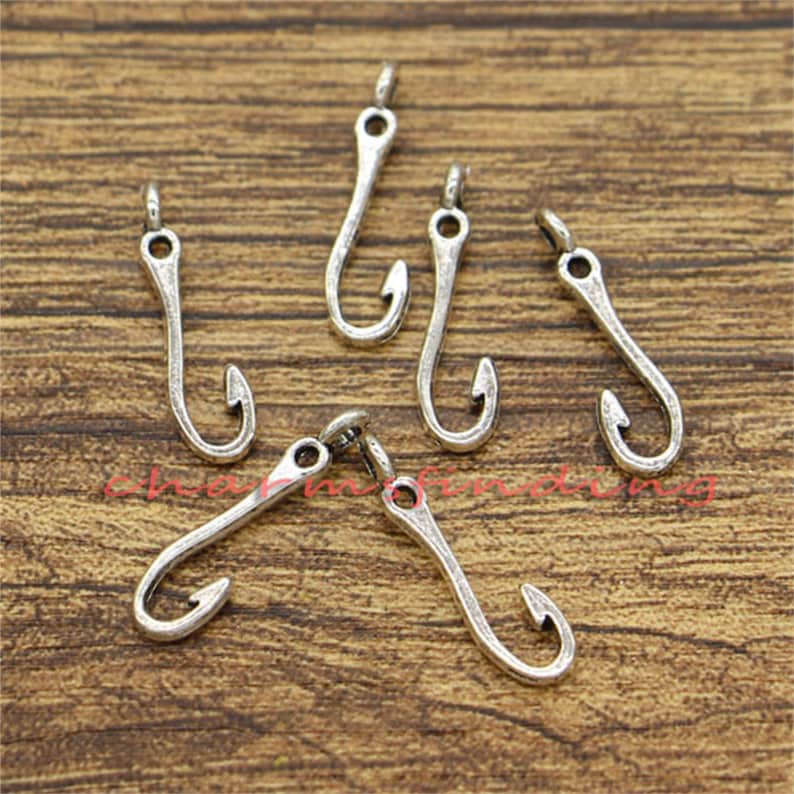 May include: Six silver-toned metal fishing hook charms. The hooks are all the same size and shape, with a small loop at the top for attaching to jewelry or other crafts.