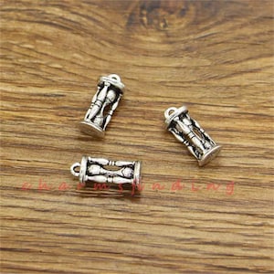 May include: Three silver charm pendants shaped like bowling pins in a glass bottle. The charms are detailed with a bowling ball and pins.