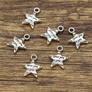Peut inclure: Six breloques en forme d'étoile argentées avec les mots "love you" répétés sur chaque breloque.