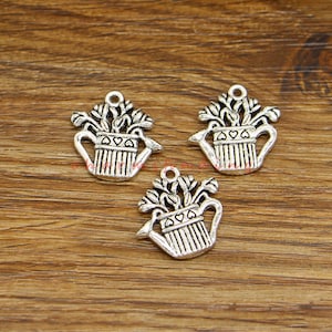 May include: Three silver charm pendants shaped like watering cans with flowers and leaves. Each charm has a heart design on the side of the watering can.
