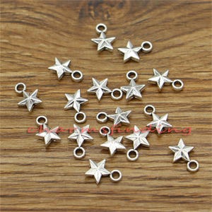 May include: A collection of silver-toned star-shaped charms with a loop for attaching to jewellery or other crafts.