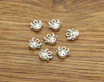 May include: Eight silver-toned metal charms shaped like cow heads with small loops for attaching to jewelry or other crafts.