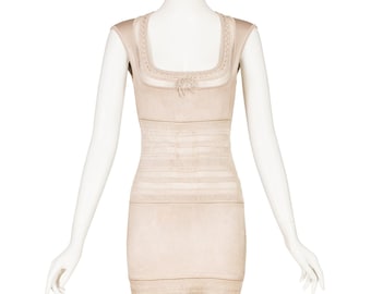 May include: A beige, sleeveless dress displayed on a mannequin. The dress features a square neckline with a bow detail and a fitted silhouette. Horizontal and vertical knit patterns create texture throughout the garment. The dress is knee-length.
