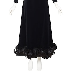 May include: A black velvet dress with a long sleeve and a feather trim at the hem.