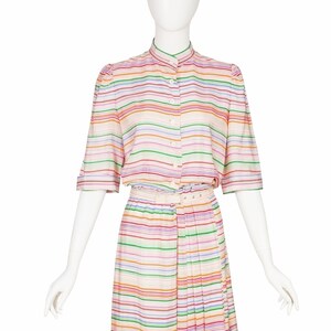 May include: A striped dress with a white background and colorful stripes. The dress has a button-up top and a skirt with pleats. The dress is belted at the waist.