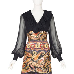 May include: A black long-sleeved dress with a ruffled neckline and sheer sleeves. The skirt is a paisley print with gold, red, and blue accents.