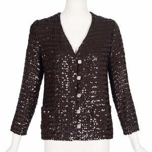 May include: A brown sequined jacket with a v-neck and button closure. The jacket has a pocket on each side and is adorned with silver buttons.