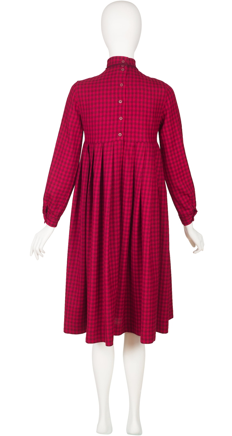 May include: A red and black gingham dress with long sleeves and a gathered skirt.