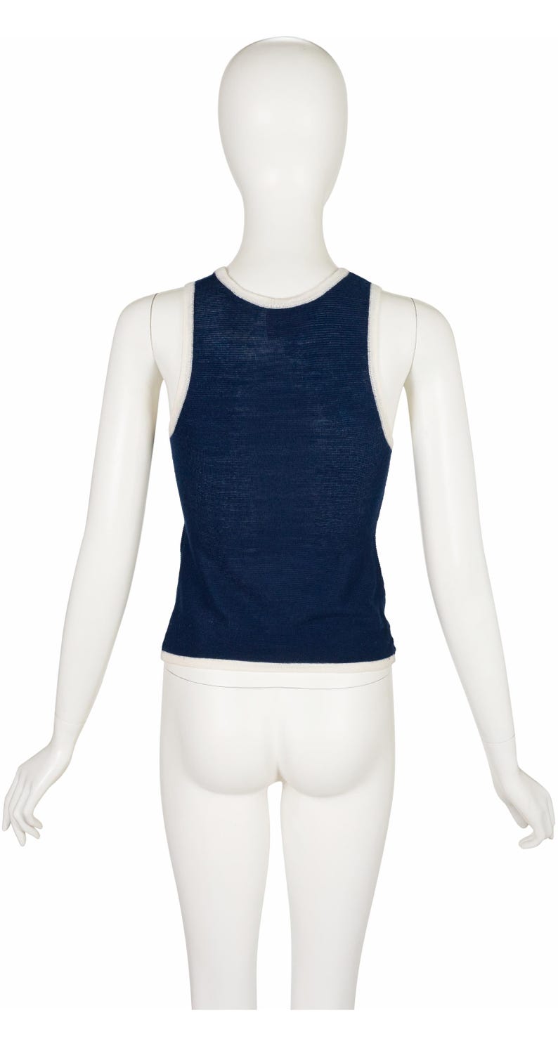 Peut inclure: D&eacute;bardeur bleu marine avec bordure blanche, pr&eacute;sent&eacute; sur un mannequin. Le haut sans manches a une encolure d&eacute;gag&eacute;e et une bordure blanche contrastante le long de l'encolure et des emmanchures. Vue arri&egrave;re du haut.