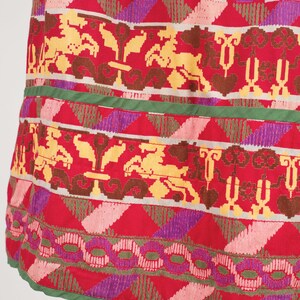 May include: A red skirt with a colorful geometric pattern. The pattern features a variety of shapes and colors, including pink, yellow, green, and purple.