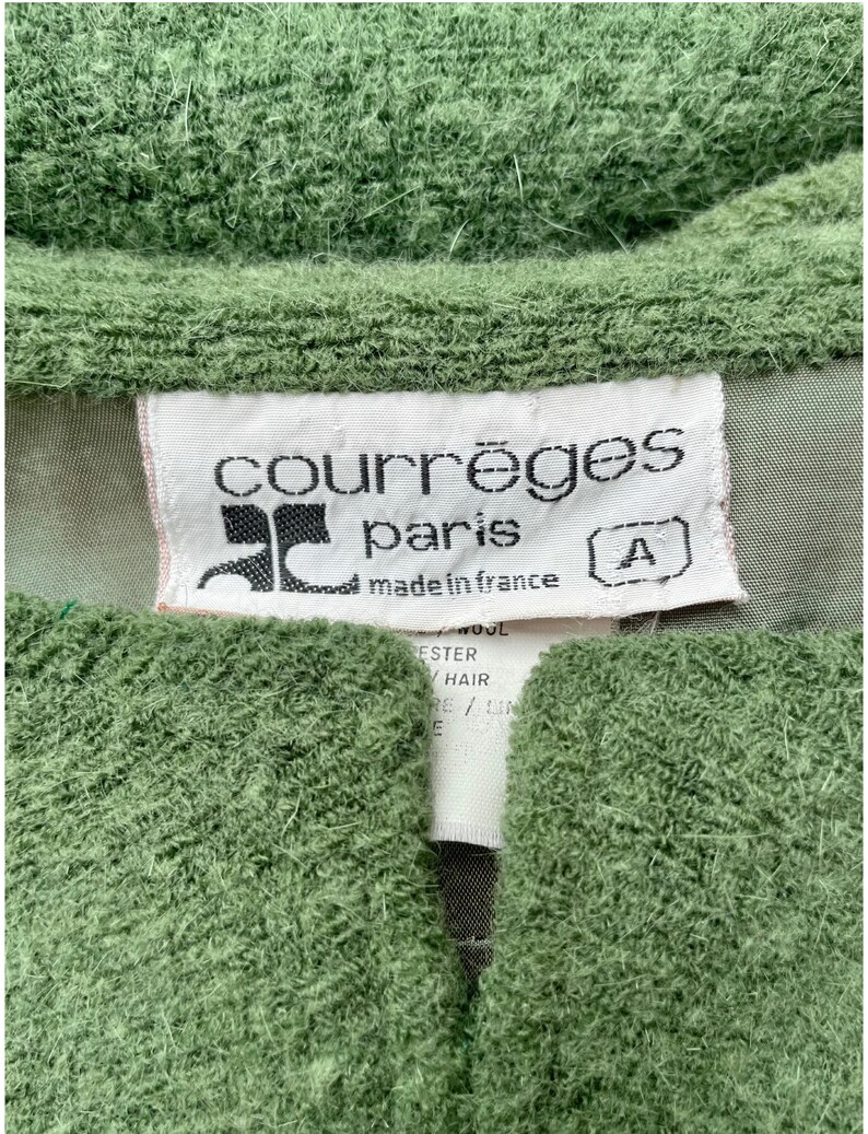 Puede incluir: Un su&eacute;ter verde con una etiqueta blanca que dice "Courr&egrave;ges Paris made in France" y una etiqueta de talla que dice "A".
