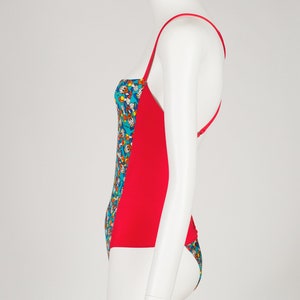 May include: A red and blue swimsuit with a colorful cartoon print. The swimsuit has a halter top and a low back.