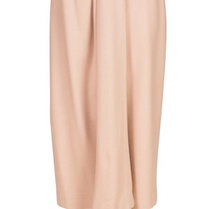 May include: A pale peach skirt with a high waist and a central pleat. The knee-length skirt is made of a smooth, solid fabric. The skirt is displayed on a white mannequin.