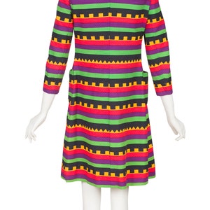 May include: A knee-length coat featuring a vibrant horizontal striped pattern in shades of purple, bright green, red, and yellow. The garment includes a collar, three-quarter length sleeves, and two side pockets, showcasing a textured fabric finish.