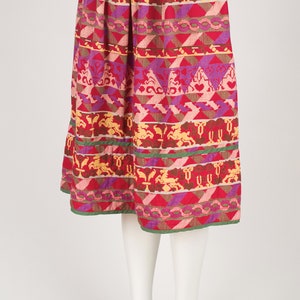 May include: A colorful midi skirt with a geometric pattern in shades of pink, red, yellow, and green. The skirt has a gathered waistband and a flowing silhouette.