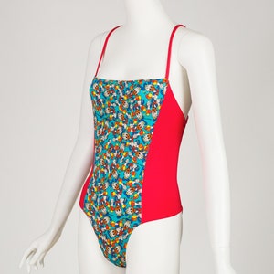 May include: A red and turquoise one-piece swimsuit with a cartoon print of a character with yellow gloves and a red hat.