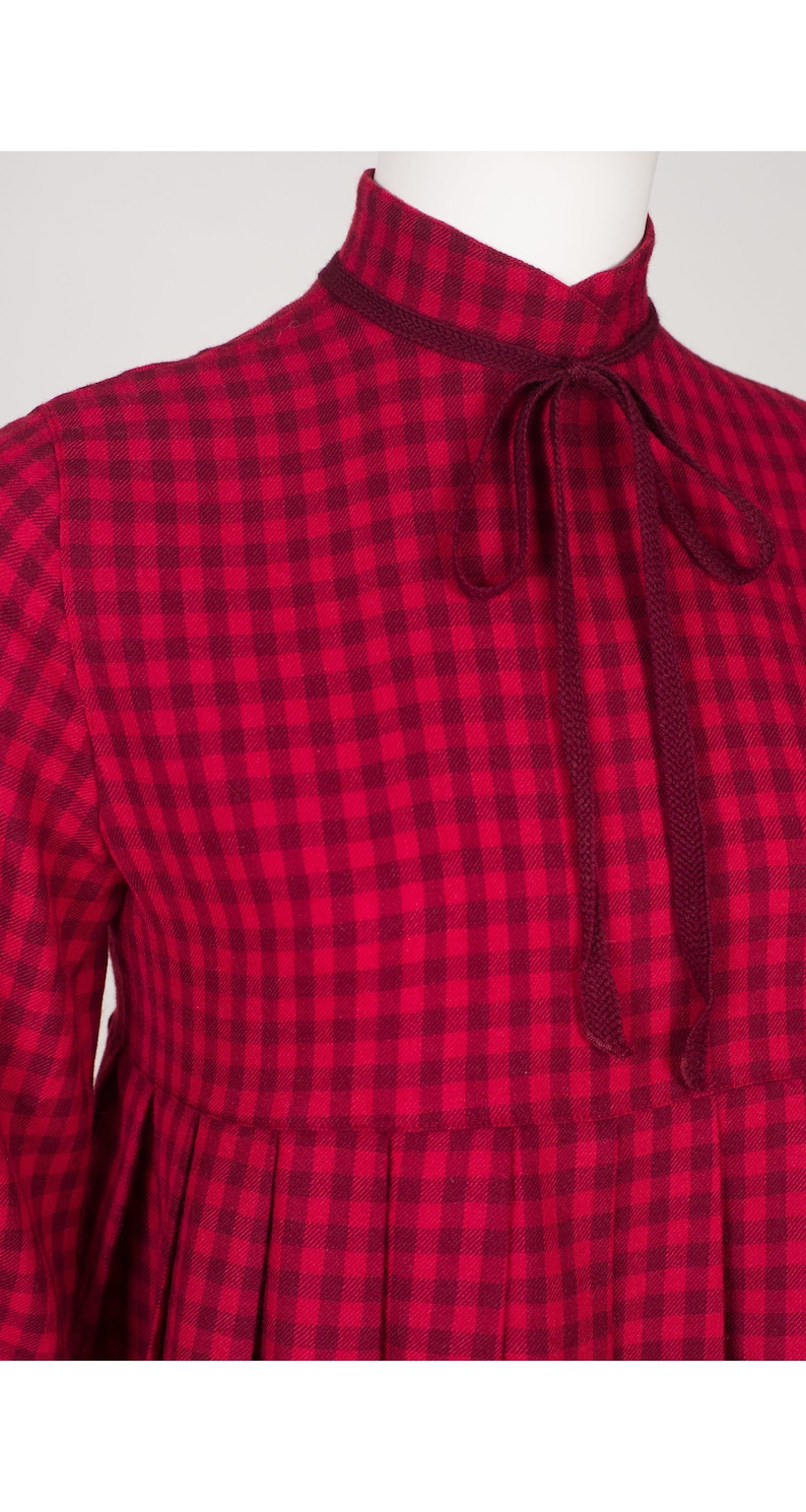 May include: A red and white gingham dress with a long sleeve and a tie at the neck.