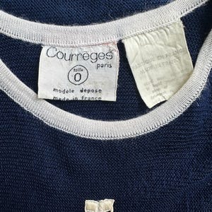 Peut inclure: Haut en maille bleu marine avec une bordure blanche autour de l'encolure et des manches. L'&eacute;tiquette indique "Courr&egrave;ges paris" et "made in france". Un petit logo blanc brod&eacute; est visible en bas.